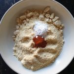 Voeg amandelmeel, bakpoeder en cayenne peper aan de geraspte parmezaanse kaas toe