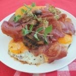 Wit bord vol met gebakken eieren, spek, worstje, tomaten en champignons gegarneerd met verse kruiden