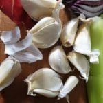 Snijplank met teentjes knoflook met velletje er nog omheen