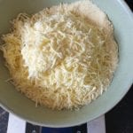 Stenen kom met toegevoegde geraspte mozzarella op keukenweegschaal