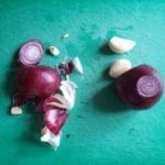 Groene snijplank met rode ui en teentjes knoflook