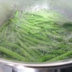 Pan met sperzieboontjes in laagje water