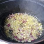 Gietijzeren braadpan met daarin ui en knoflook