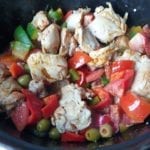 Gietijzeren braadpan met kip, olijven, paprika en tomaten