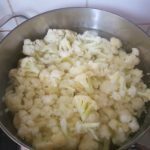 De in kleine stukjes gesneden bloemkoolstronk met de bloemkoolroosjes in water met wat zout bijtgaar koken.
