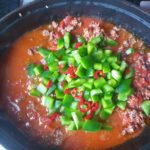 Braadpan waar groene paprika en chili peper aan toegevoegd is