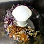 Kom van een keukenmachine met ui, knoflook en specerijen