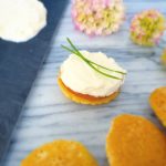 Leg op elke blini een plakje zalm, een flinke laag roomkaas en garneer met wat bieslook