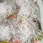 Parmezaanse kaas over de pesto raspen