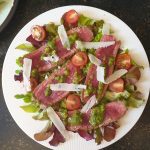 Strooi de Parmigiano Reggiano en de pijnboompitten over de tagliata di manzo
