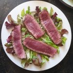 leg een aantal plakken ossenhaas op het bed van rucola en pluksla