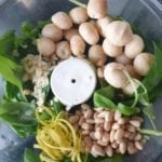 Kom van keukenmachine met macadamia nootjes, pijnboompitten, basilicum, citroenzest en knoflook
