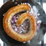 Koekenpan met braadworst en stukjes ui