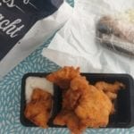 Tafel met portie kibbeling met saus en harinkjes in de achtergrond