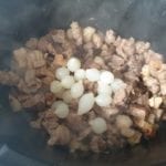 Braadpan met gebruind vlees en zilveruitjes