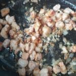 Uitgebakken spekblokjes met gefruite sjalot in een braadpan