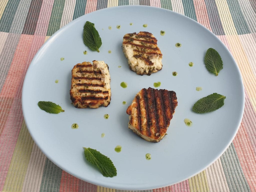 Bord met drie stukken gegrilde halloumi en groene saus