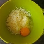 Groen kom met geraspte mozzarella en een ei