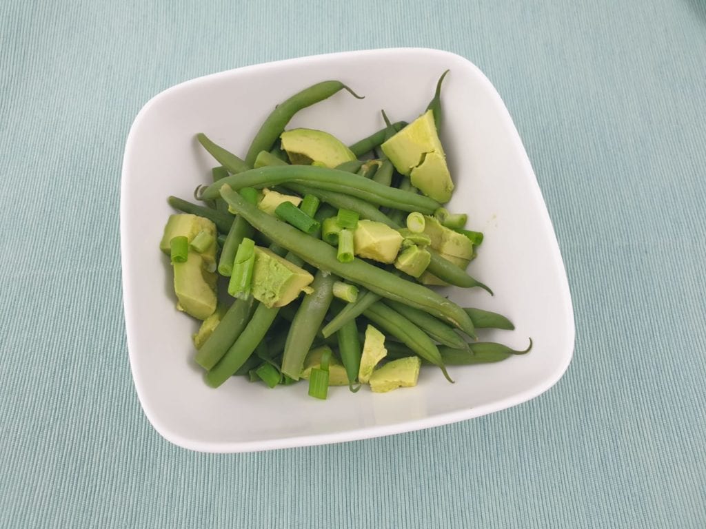 Kom met sperzieboontjes met avocado blokjes